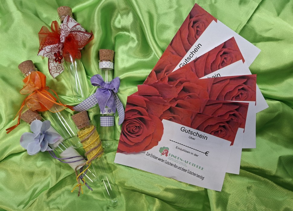 Geschmückte Reagenzgläschen und Gutscheine der Linden-Apotheke Niefern-Öschelbronn auf grünem Stoff