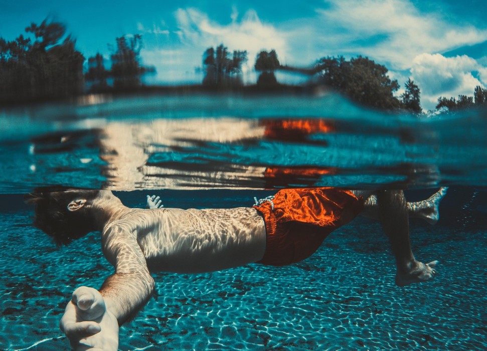 Junger Mann der auf dem Rücken schwimmt