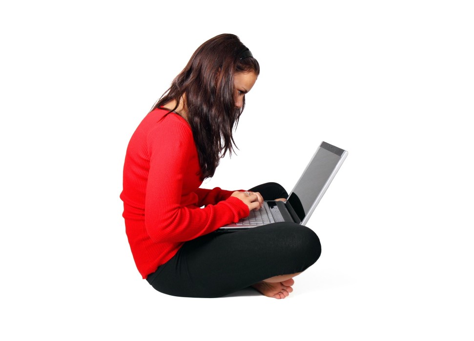 Frau sitzt im Schneidersitz mit einen Laptop auf dem Schoß