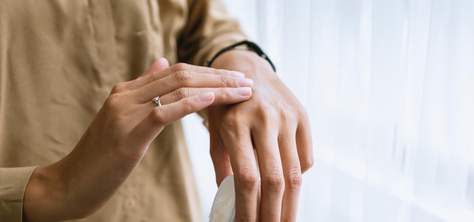 Frau cremt sich die Hand ein