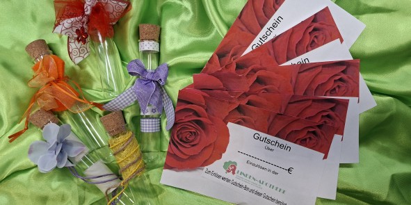 Geschmückte Reagenzgläschen und Gutscheine der Linden-Apotheke Niefern-Öschelbronn auf grünem Stoff