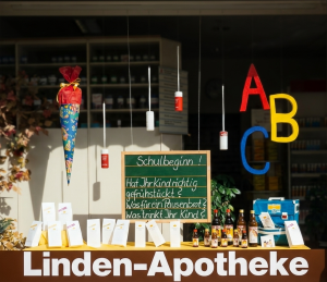 Schaufenster mit einer Tafel mit den Schriftzug Schulbeginn, bunten Buchstaben, Tornister und Schultüte 