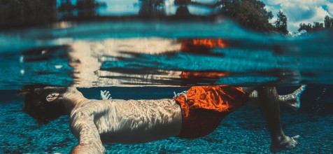 Junger Mann der auf dem Rücken schwimmt